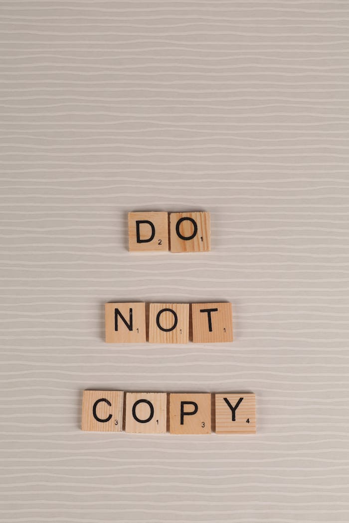 about-01 Scrabble tiles arranged as 'Do Not Copy' on a neutral background, conveying originality message.